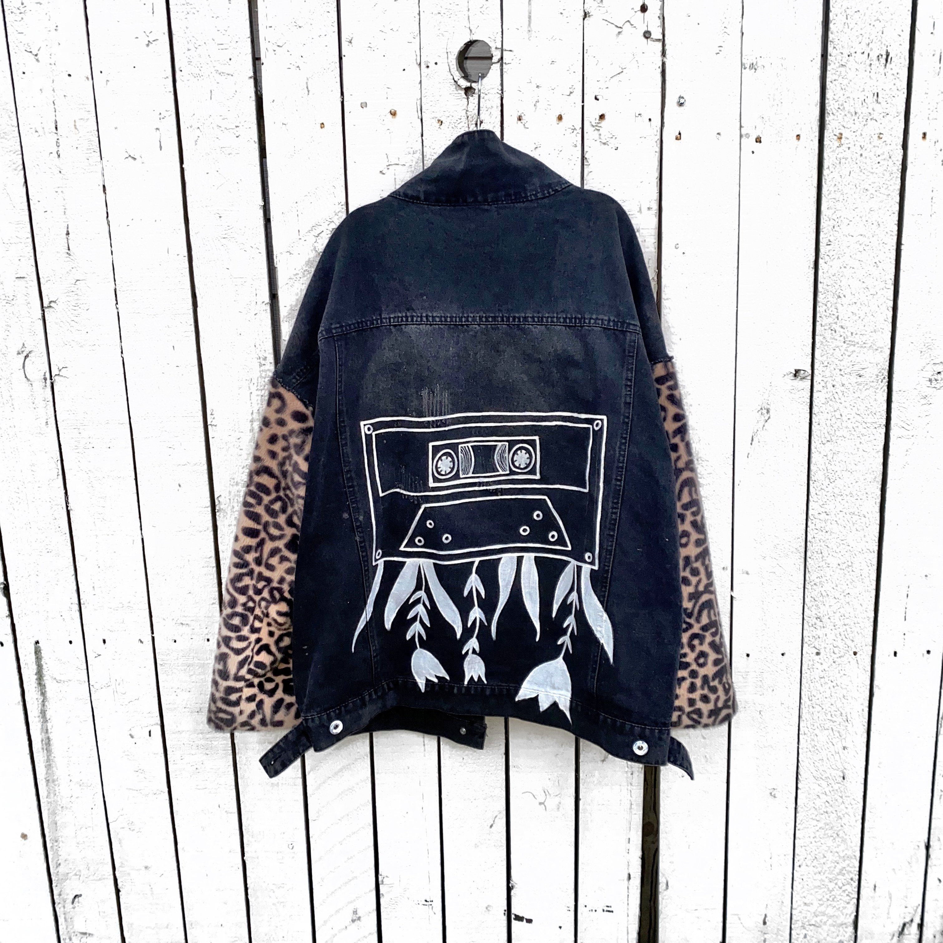 Black denim jacket with super comfortable leopard pattern sleeves. Large white cassette tape painted on back, with white flowers and leaves sprouting out. Signed @wrenandglory.