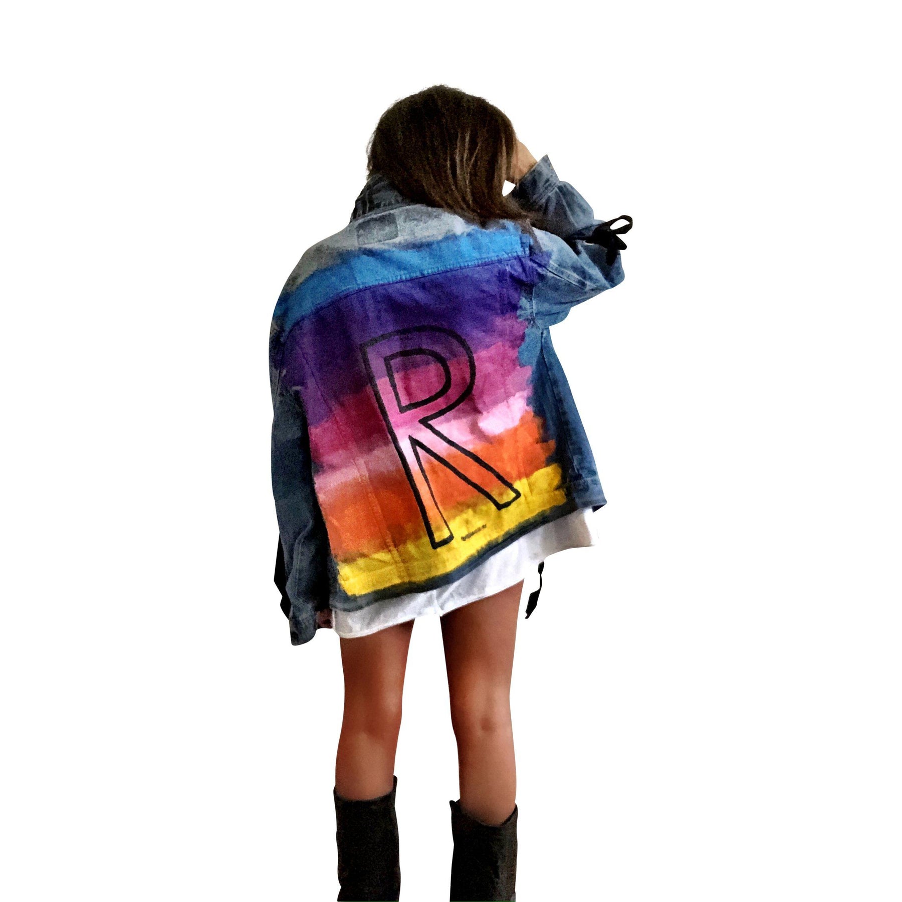 Dark blue denim wash, with velvert ribbon threaded through arms and front, lower left side. Ombre of colored striped on back, with large black initial painted in open block font over the colors. 'BE THE MAGIC' painted on color in black. Please specify initial above. Signed @wrenandglory.