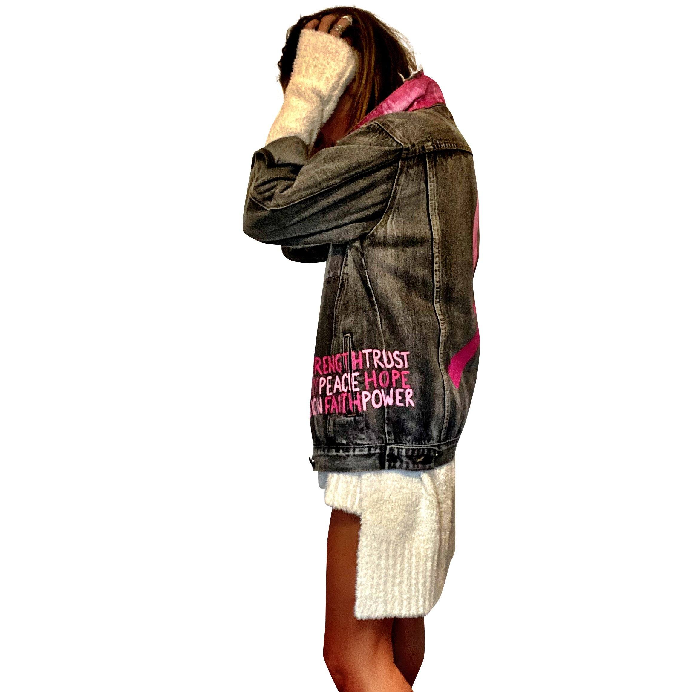 Faded black denim. Pink ombre Breast Cancer ribbon painted in large on back. Love, Strength, Trust, Beauty, Peace, Hope, Passion, Faith, Power painted in light & bright pink on the front. Collar painted in pink ombre. Signed @wrenandglory.