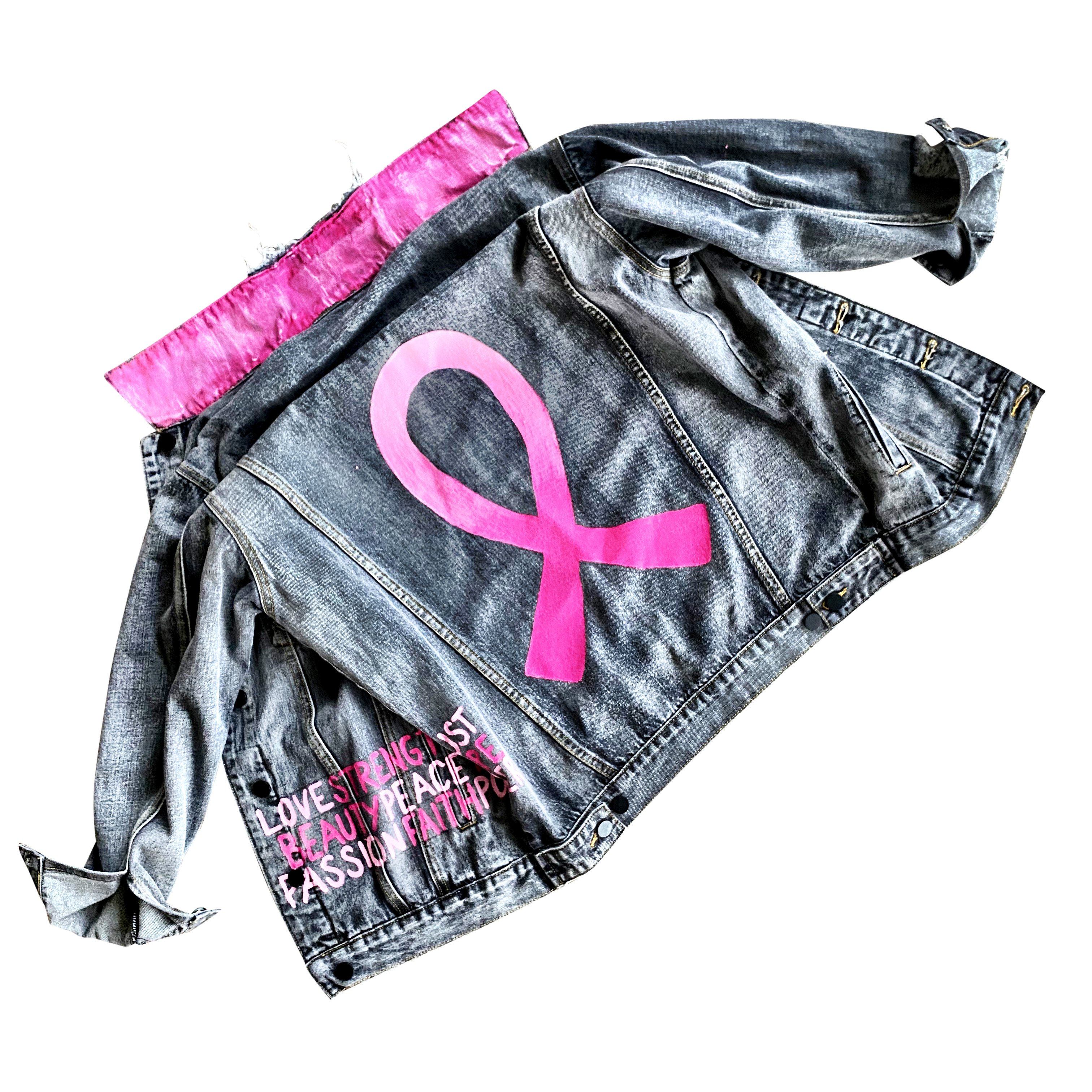 Faded black denim. Pink ombre Breast Cancer ribbon painted in large on back. Love, Strength, Trust, Beauty, Peace, Hope, Passion, Faith, Power painted in light & bright pink on the front. Collar painted in pink ombre. Signed @wrenandglory.