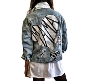 Lighter blue denim wash. Large white heart on back with MAMA painted inside in black. Smaller black hearts surrounding the larger one, customized with kids names. Collar and front pockets painted white. Signed @wrenandglory.
