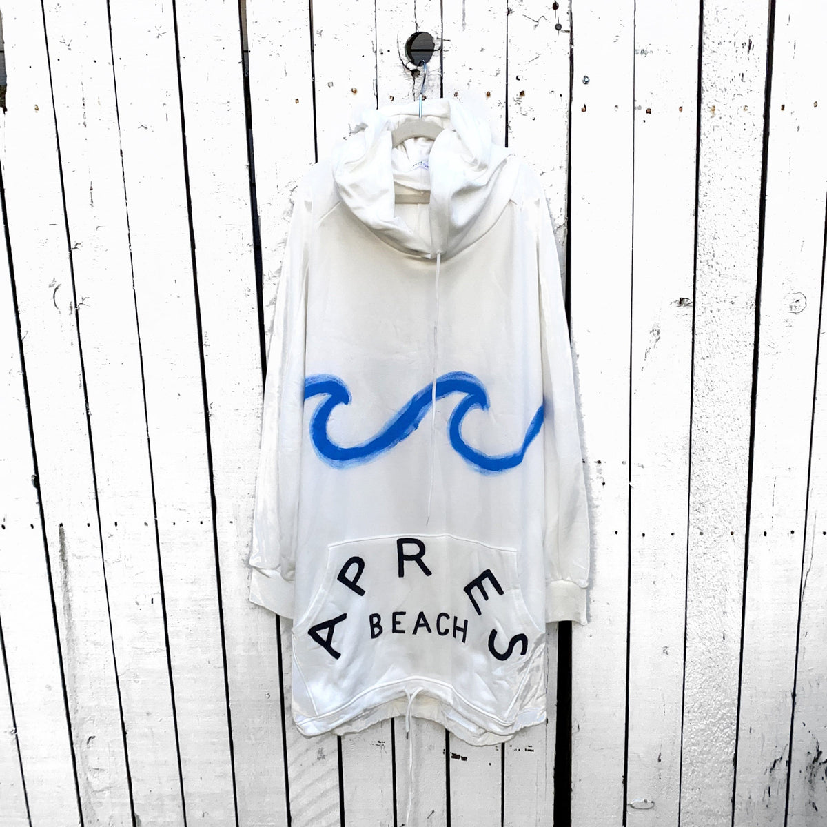 Oversized white sweatshirt dress. Blue wave painted along entire sweatshirt, on chest area, with APRES BEACH painted in black on front pocket. Signed @wrenandglory.