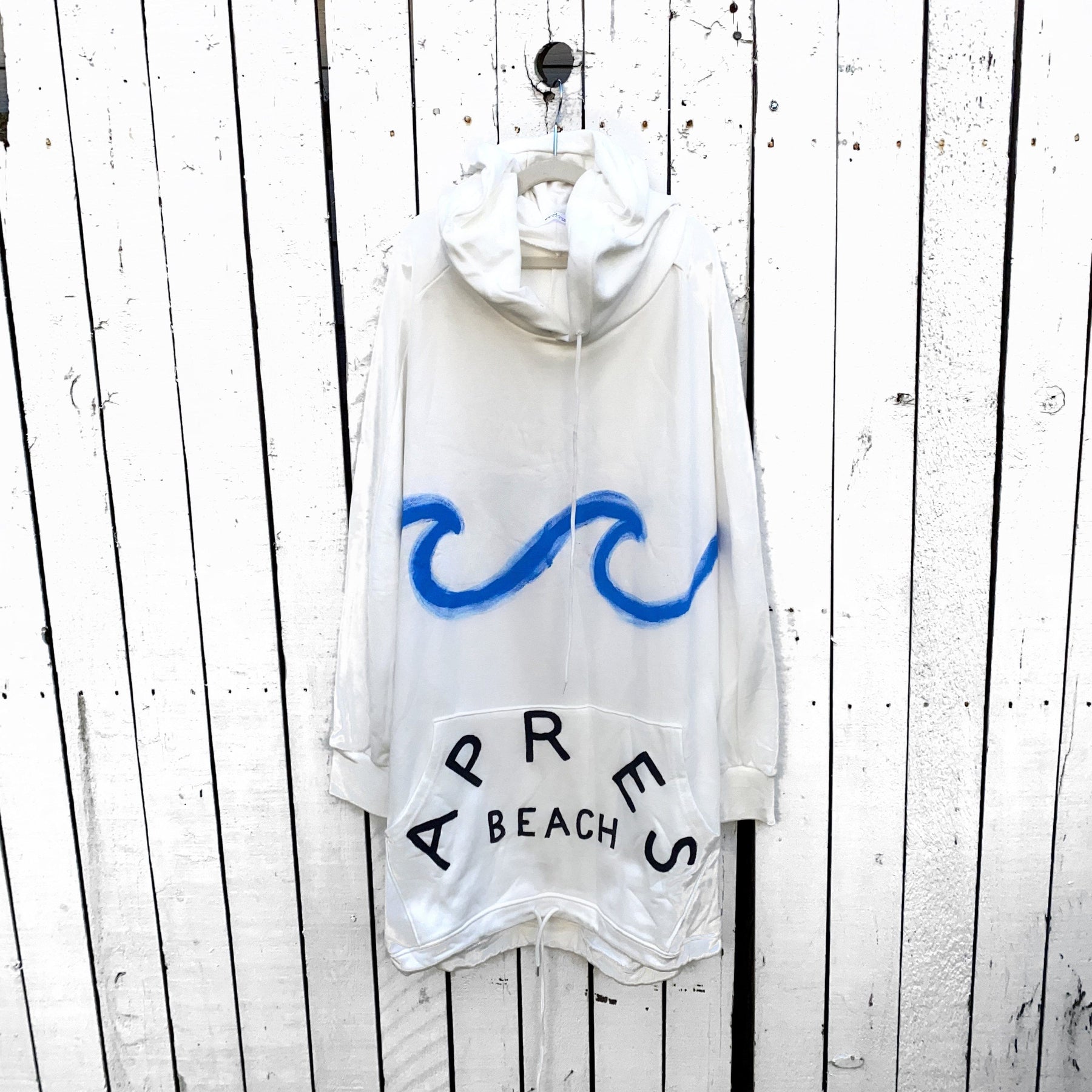 Oversized white sweatshirt dress. Blue wave painted along entire sweatshirt, on chest area, with APRES BEACH painted in black on front pocket. Signed @wrenandglory.