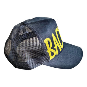 Black lack trucker hat with BACK UP painted on hat in yellow. Signed @wrenandglory