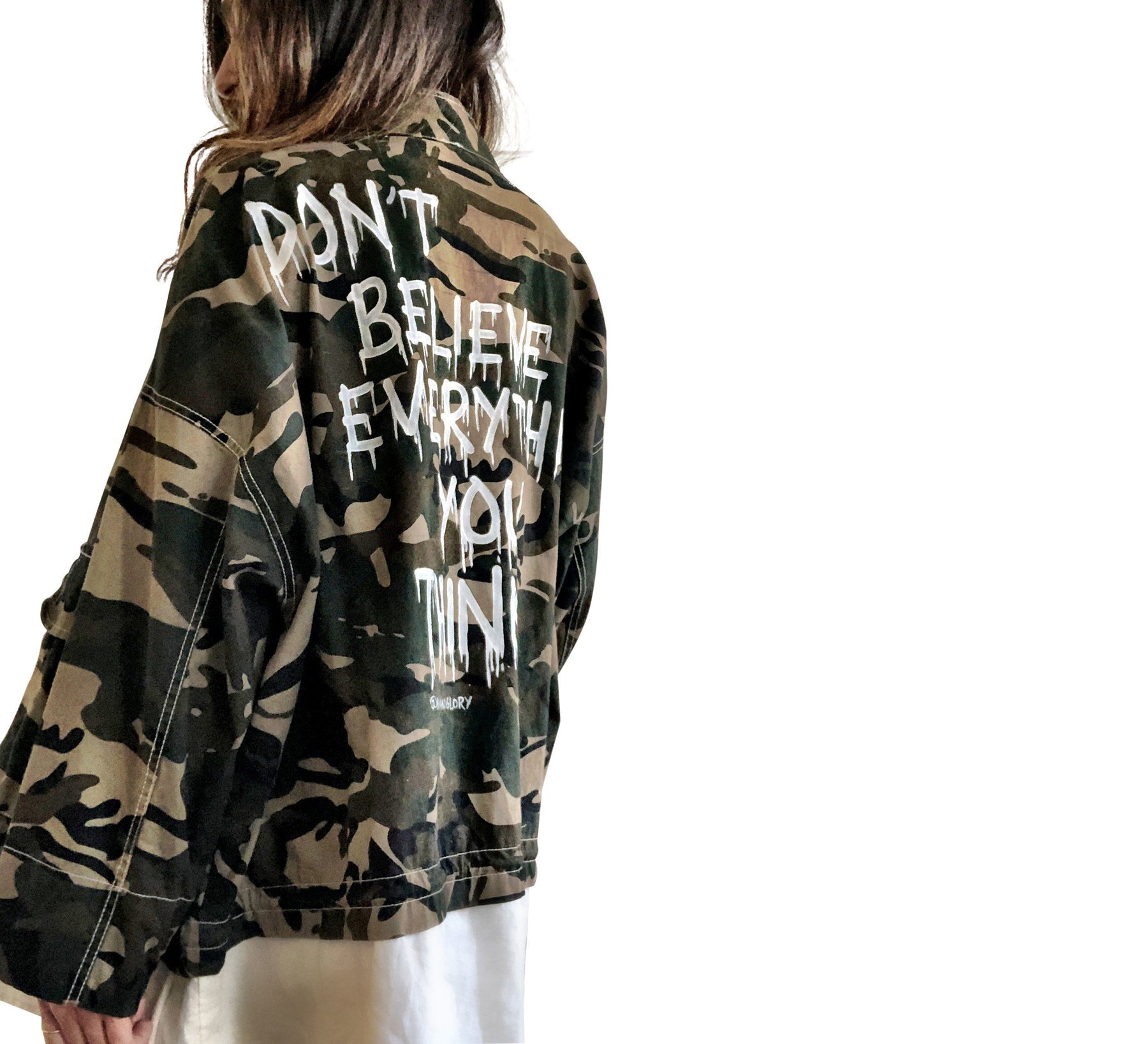 Camo print oversized denim jacket with off white layer inside. DON'T BELIEVE EVERYTHING YOU THINK painted on the back in white, drip effect font. Signed @wrenandglory.
