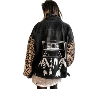 Black denim jacket with super comfortable leopard pattern sleeves. Large white cassette tape painted on back, with white flowers and leaves sprouting out. Signed @wrenandglory.