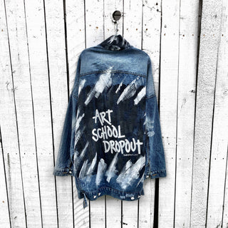 Dark blue denim jacket with long back. White and black pattern painted on back, with ART SCHOOL DROPOUT painted over it in white. Collar and front pockets painted with black and white pattern. Signed @wrenandglory.