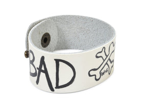 Hand made leather bracelet, hand painted with Bad B*tch and crossbones.  White leather, black paint. Signed W+G