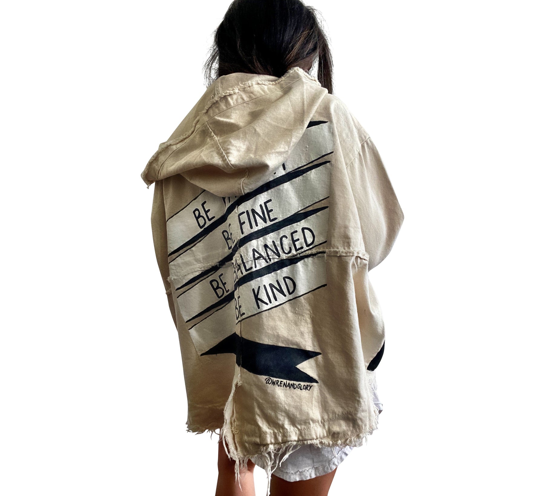 Beige hooded denim jacket. BE PATIENT, BE FINE, BE BALANCED, BE KIND painted on back, in a black and white banner. Signed @wrenandglory.