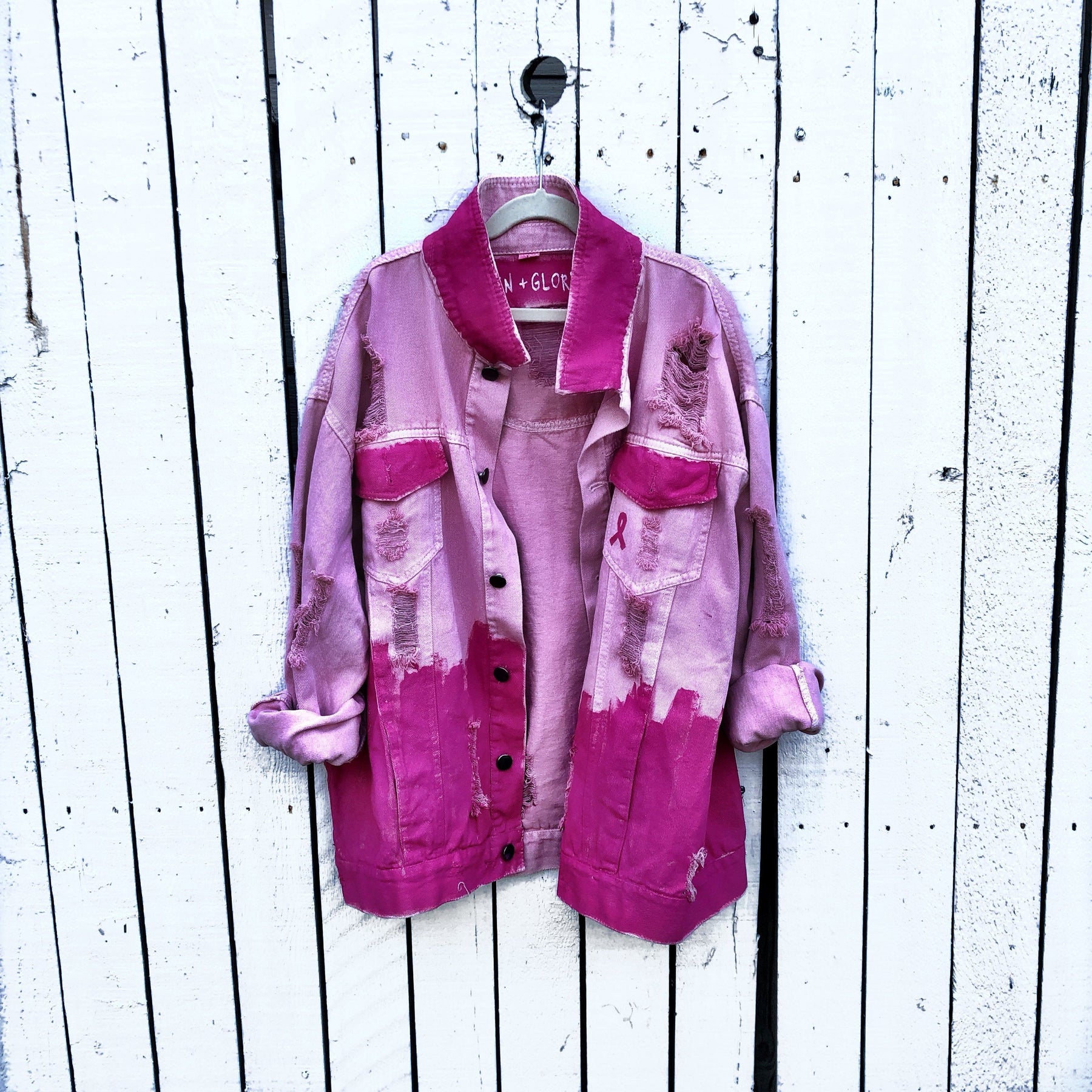 Pink /blush colored denim. Hot pink painted along the bottom half of the jacket, with FIGHT LIKE A GIRL painted in white on back. Small Breast Cancer Awareness ribbon painted on front upper pocket. Signed @wrenandglory.