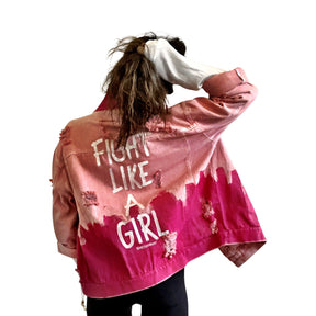 Pink /blush colored denim. Hot pink painted along the bottom half of the jacket, with FIGHT LIKE A GIRL painted in white on back. Small Breast Cancer Awareness ribbon painted on front upper pocket. Signed @wrenandglory.