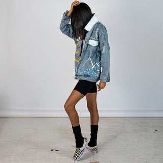 Lighter blue denim wash. Outline of mountain range, ocean waves, and sun setting surrounding entire jacket. Collar and front pockets painted white. Signed @wrenandglory.