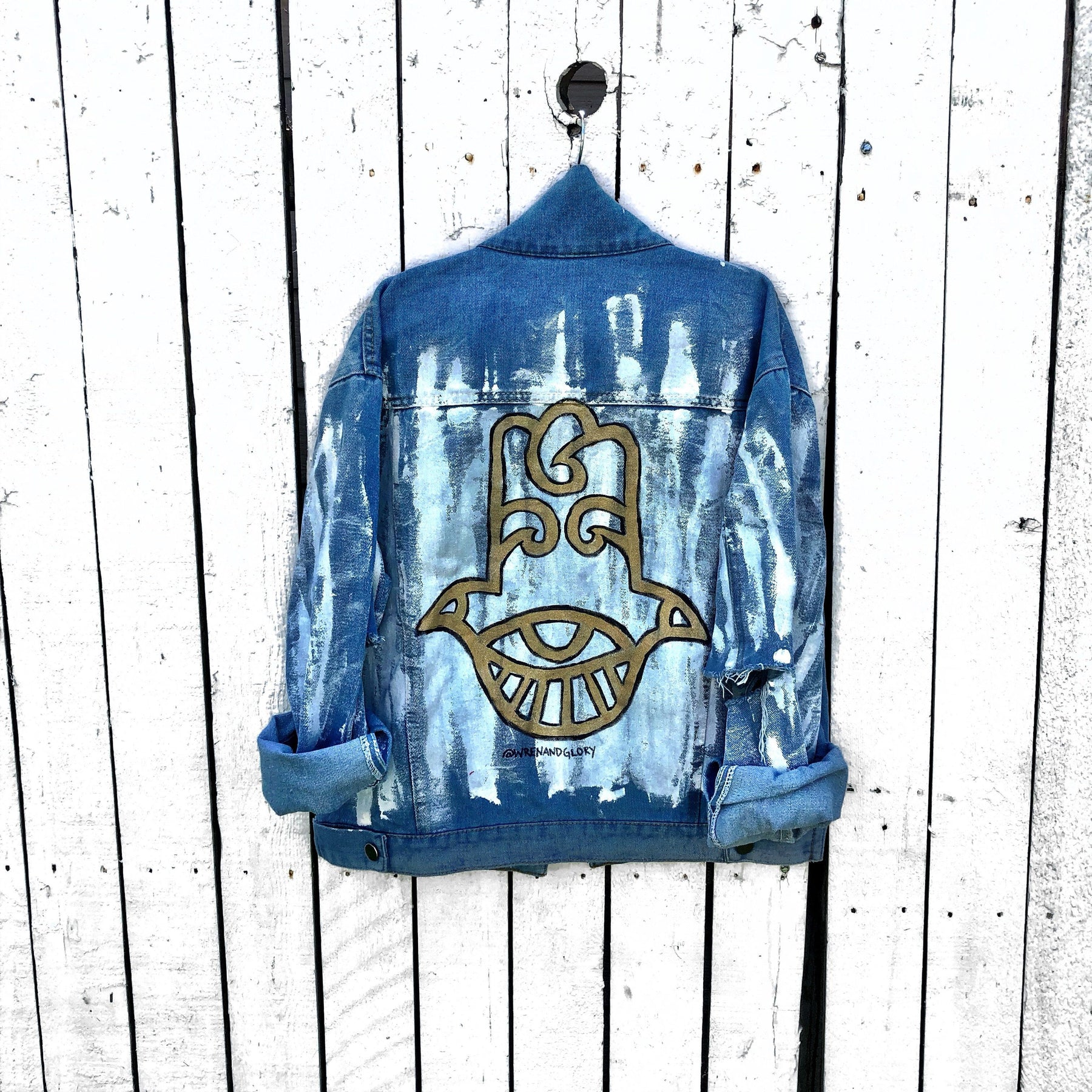 Medium blue denim wash. 'White base all over, with black and gold Hamsa painted on the back. Signed @wrenandglory.