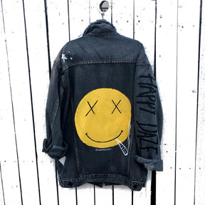 Yellow smiley on faded black denim jacket, with hand painted symbols throughout. Hand painted with white, yellow and black. 'HAPPY DAZE' written down left arm. Signed @wrenandglory