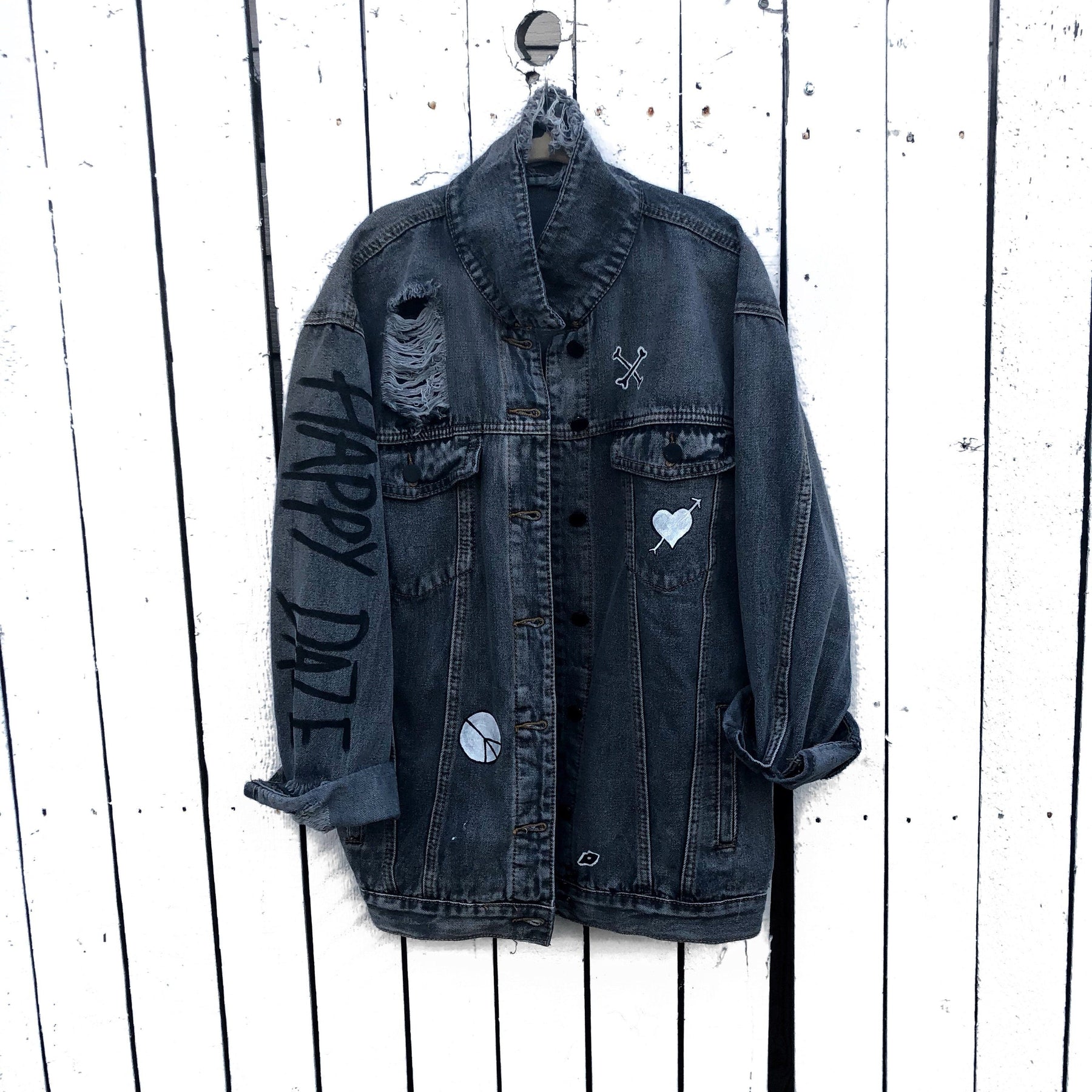 Yellow smiley on faded black denim jacket, with hand painted symbols throughout. Hand painted with white, yellow and black. 'HAPPY DAZE' written down left arm. Signed @wrenandglory