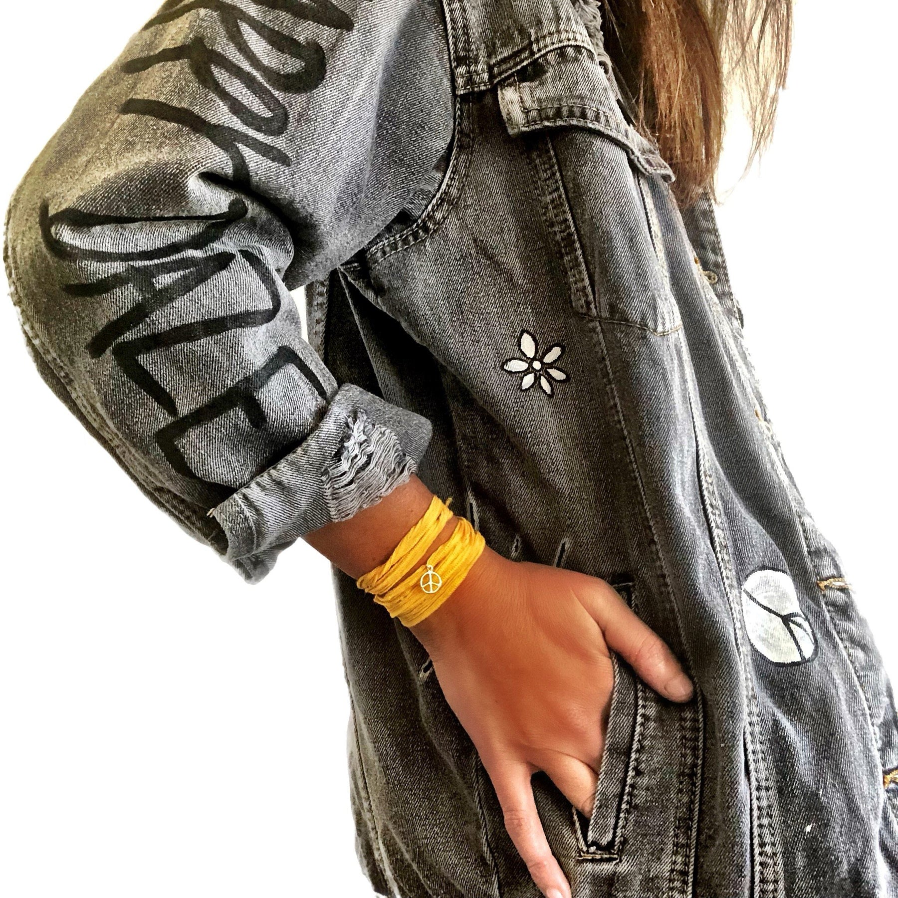 Yellow smiley on faded black denim jacket, with hand painted symbols throughout. Hand painted with white, yellow and black. 'HAPPY DAZE' written down left arm. Signed @wrenandglory