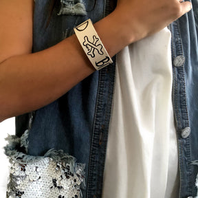 Hand made leather bracelet, hand painted with Bad B*tch and crossbones.  White leather, black paint. Signed W+G