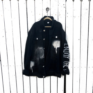 Black denim. Initial on back in white, with white and black painted 'splatters' 'Enjoy The Ride' painted in white down the arm Signed @wrenandglory.