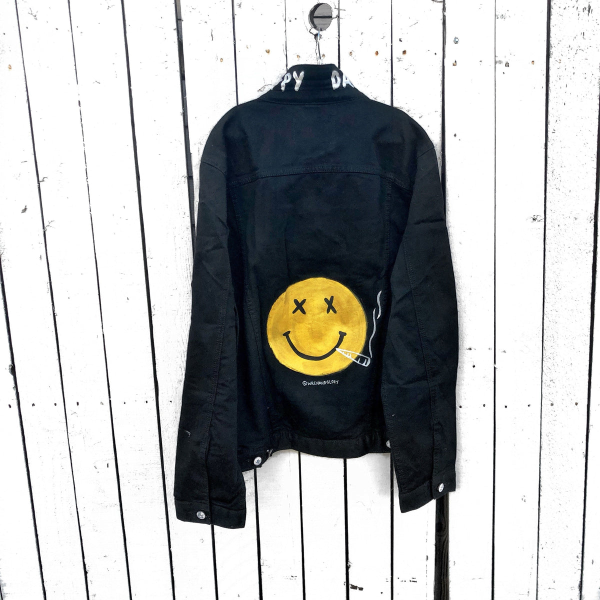 Black denim. Yellow smiley with smoking utensil on back. Happy Daze painted on collar in white. Signed @wrenandglory.