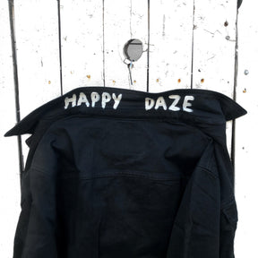 Black denim. Yellow smiley with smoking utensil on back. Happy Daze painted on collar in white. Signed @wrenandglory.