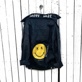 Black denim. Yellow smiley with smoking utensil on back. Happy Daze painted on collar in white. Signed @wrenandglory.