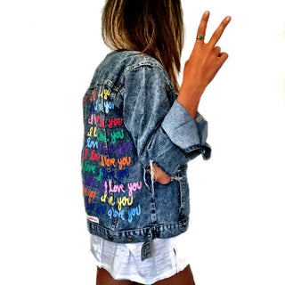 Medium blue denim wash. 'I Love You' painted in rainbow cursive, over and over. White painted pockets and collar, with dripping heart on arm. Signed @wrenandglory.
