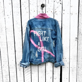 Light blue denim wash. Large pink ribbon, in honor of Breast Cancer, with 'Fight Like A Girl' painted on the back. Pockets and collar painted in pink Signed @wrenandglory.