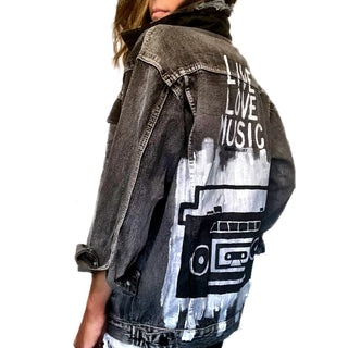 Faded black denim. Boombox painted on back over white base, with wording 'LIVE, LOVE, MUSIC'. Assorted 1 inch pins on front upper side. Signed @wrenandglory.