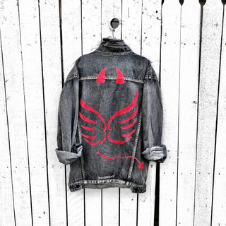 Faded black denim. Red devil wings, horns and tail painted on back, with 'devil' painted in script on front upper corner. Assorted 1 inch pins on front upper side. Signed @wrenandglory.