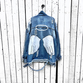 Medium blue denim wash. White angel wings and halo painted on back, with 'angel' painted on front upper corner. Color and front pockets painted white. Signed @wrenandglory.