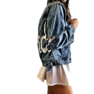 Medium blue denim wash. 'Loved' painted in white, block cursive, outlines with black on lower back, with row of assorted sized heart clusters down the back center. Signed @wrenandglory.