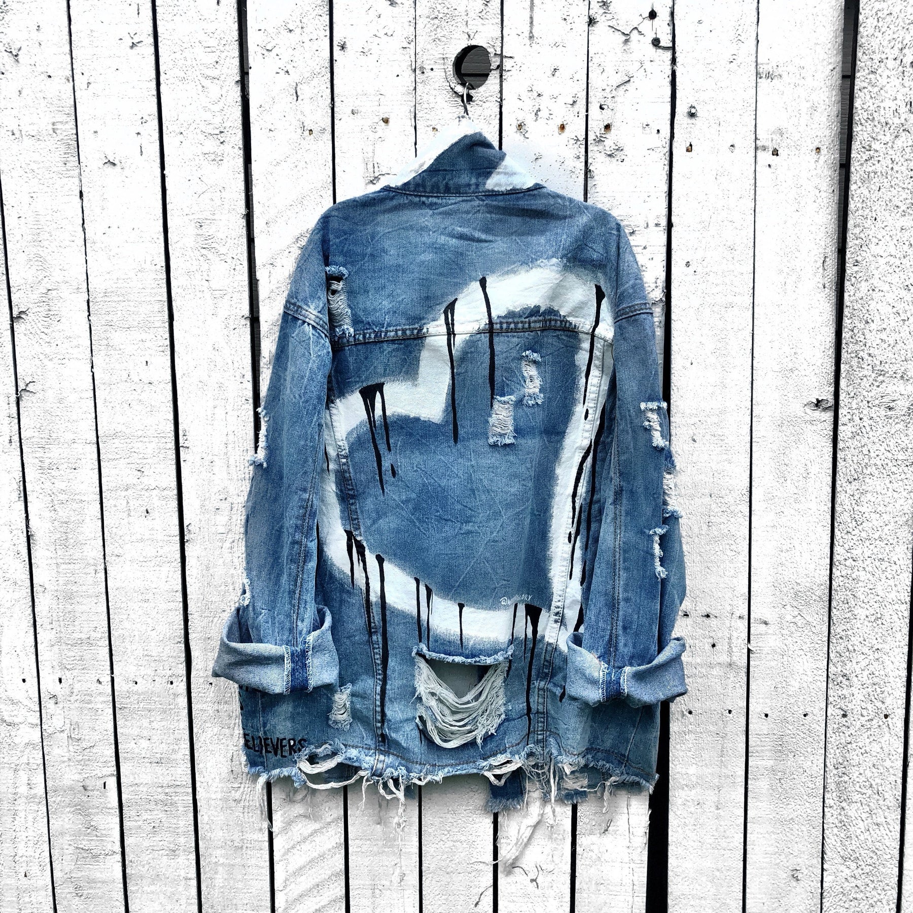 Medium blue denim wash. Large white heart painted all across back, with black dripping effect. Painted in black'Made for the lovers, beauties, artists, dreamers......' on front lower left side. White thick stripes at the collar. Signed @wrenandglory.