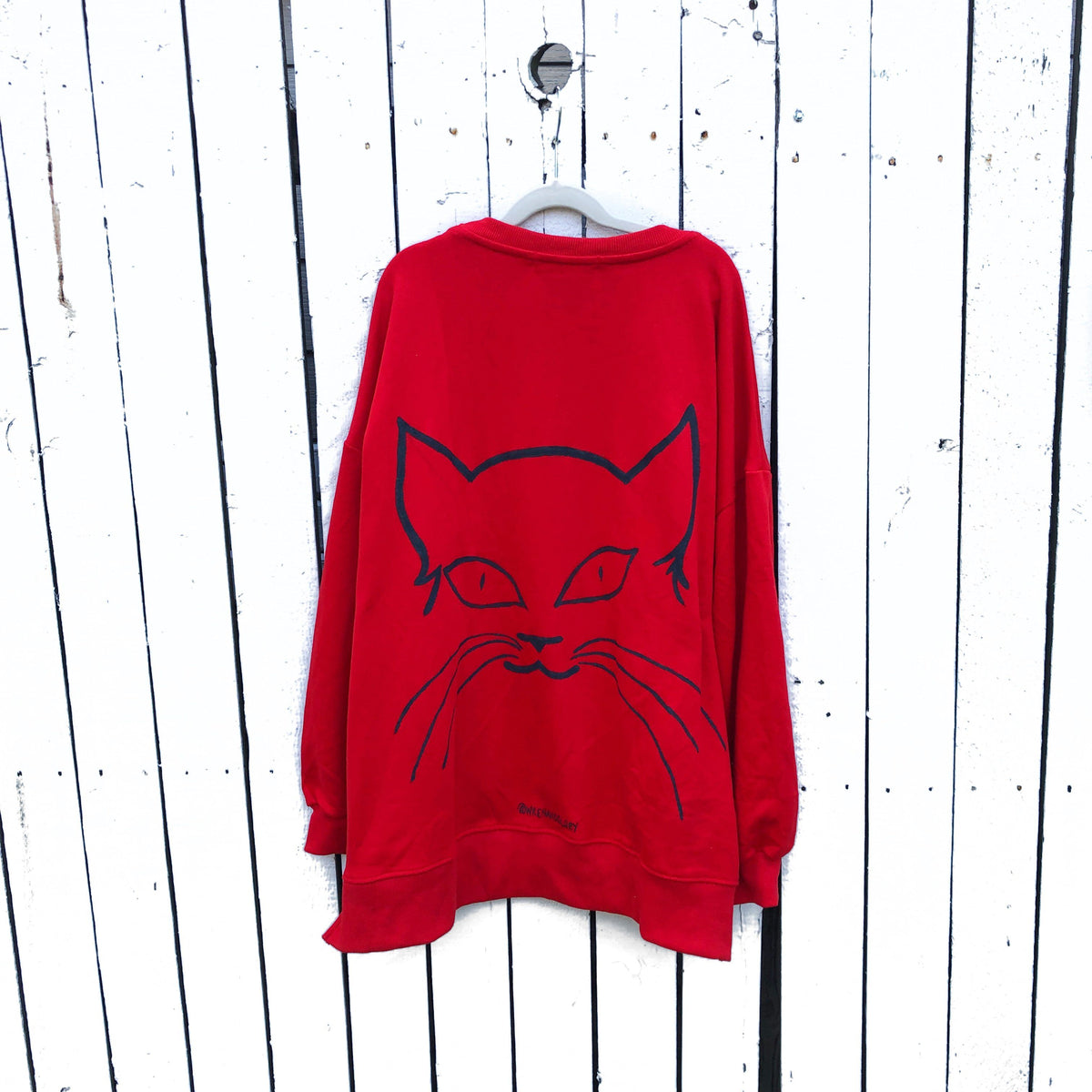 Oversized red sweatshirt. Silhouette of cat painted in black on back, with MEOW painted on front upper side. Signed @wrenandglory.