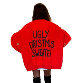 Oversized, batwing red sweatshirt with rings on sleeves. UGLY CHRISTMAS SWEATER painted on the back in black, with green paint drips coming from letters. Signed @wrenandglory