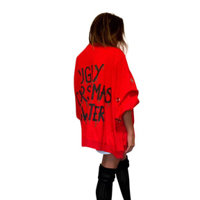 Oversized, batwing red sweatshirt with rings on sleeves. UGLY CHRISTMAS SWEATER painted on the back in black, with green paint drips coming from letters. Signed @wrenandglory