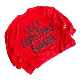 Oversized, batwing red sweatshirt with rings on sleeves. UGLY CHRISTMAS SWEATER painted on the back in black, with green paint drips coming from letters. Signed @wrenandglory