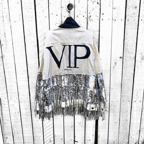 White denim jacket with black sequin fringes hanging off on bottom half of jacket, and below elbows, VIP painted in large on back. Pockets and collar painted black. Signed @wrenandglory.