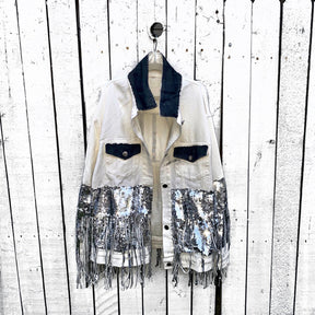 White denim jacket with black sequin fringes hanging off on bottom half of jacket, and below elbows, VIP painted in large on back. Pockets and collar painted black. Signed @wrenandglory.