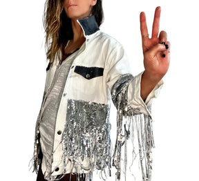 White denim jacket with black sequin fringes hanging off on bottom half of jacket, and below elbows, VIP painted in large on back. Pockets and collar painted black. Signed @wrenandglory.