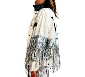 White denim jacket with black sequin fringes hanging off on bottom half of jacket, and below elbows, VIP painted in large on back. Pockets and collar painted black. Signed @wrenandglory.