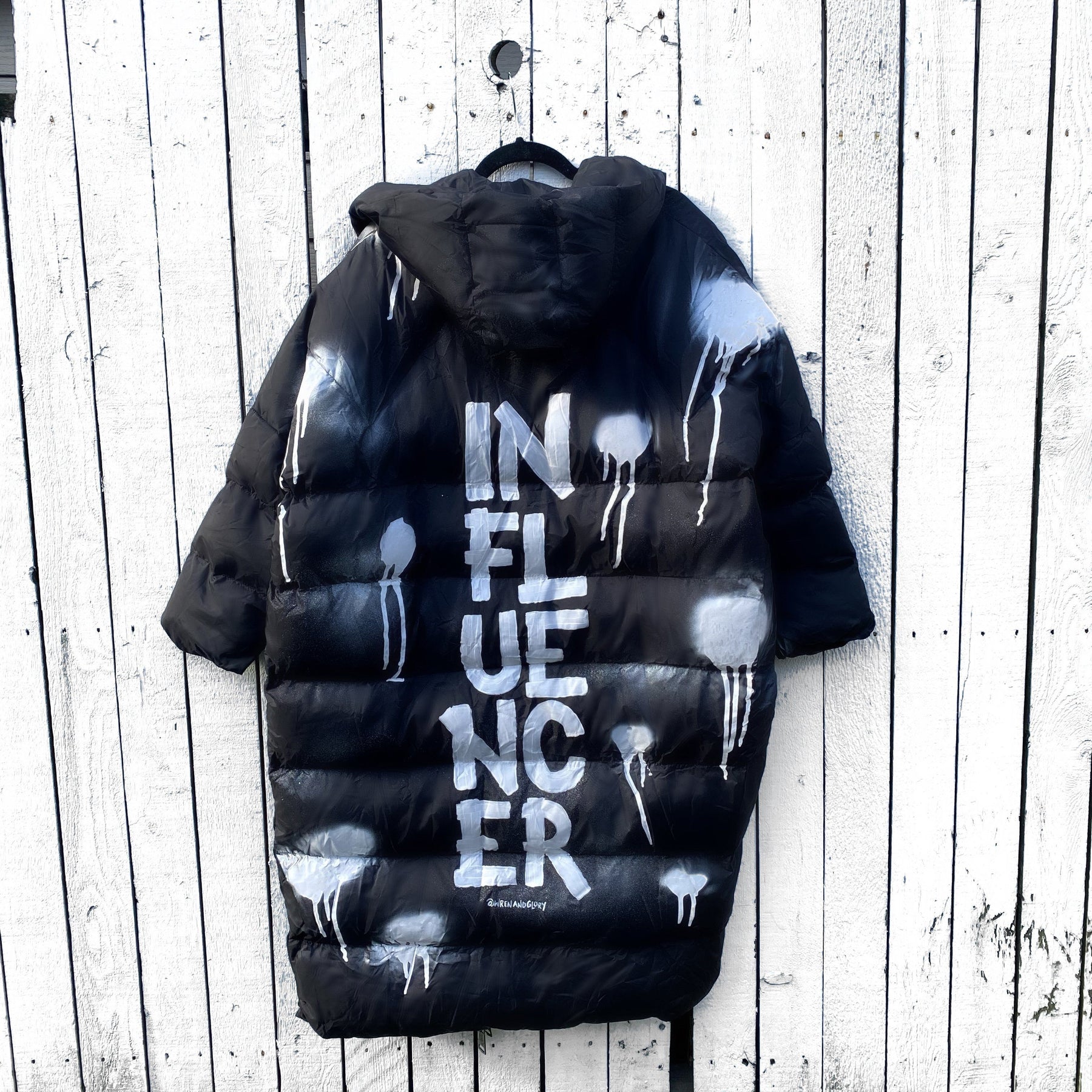 The COOLEST, MOST COMFORTABLE puffer jacket. White spray paint surrounding entire jacket, with INFLUENCER painted down the back, center, in large text. Signed @wrenandglory.