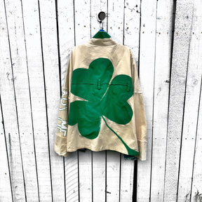 Khaki colored jacket, with green flannel print inside. Large green clover painted on back, with KISS ME down the arm in green and white. Signed @wrenandglory.