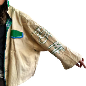 Khaki colored jacket, with green flannel print inside. Large green clover painted on back, with KISS ME down the arm in green and white. Signed @wrenandglory.