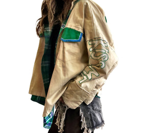 Khaki colored jacket, with green flannel print inside. Large green clover painted on back, with KISS ME down the arm in green and white. Signed @wrenandglory.