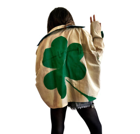 Khaki colored jacket, with green flannel print inside. Large green clover painted on back, with KISS ME down the arm in green and white. Signed @wrenandglory.