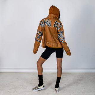 Tan, faux leather jacket with Brown hooded sweatshirt lining the inside and thumbholes at sleeves. 'F*CK DRAMA LET'S PARTY' painted along back of sleeves and upper back of jacket, in black, with white outline. Signed @wrenandglory.