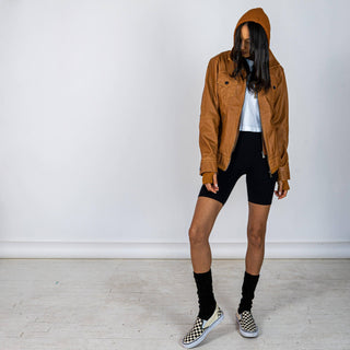 Tan, faux leather jacket with Brown hooded sweatshirt lining the inside and thumbholes at sleeves. 'F*CK DRAMA LET'S PARTY' painted along back of sleeves and upper back of jacket, in black, with white outline. Signed @wrenandglory.