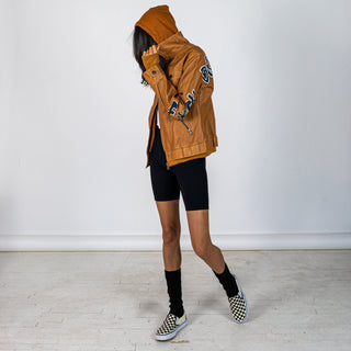 Tan, faux leather jacket with Brown hooded sweatshirt lining the inside and thumbholes at sleeves. 'F*CK DRAMA LET'S PARTY' painted along back of sleeves and upper back of jacket, in black, with white outline. Signed @wrenandglory.