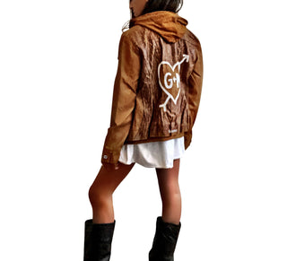 Light brown, faux leather jacket with tan sweatshirt lining the inside, with good and thumbholes at sleeves. Tree trunk painted across entire back in dark brown, with heart carved out and ' ___ + ___' painted inside. Please specify names above. Signed @wrenandglory.