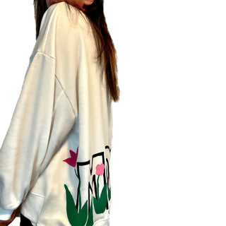 Oversized white sweatshirt. 'MOM' painted in on back, coming up from bottom hem, with flower pattern painted throughout letters. Customized upper back with names of children, grandchildren, husband, etc. Up to 8 names able to be painted. Small red embroidered heart on each lower sleeve. Signed @wrenandglory.